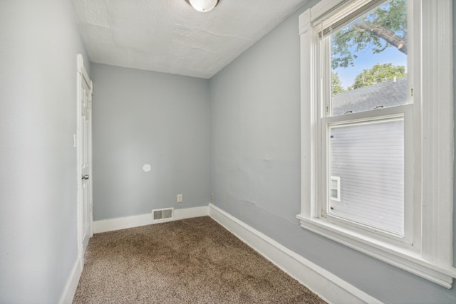 unfurnished room featuring a textured ceiling and carpet