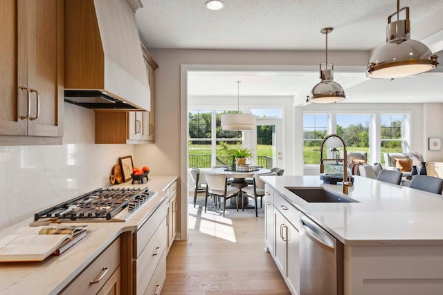 kitchen featuring a wealth of natural light, appliances with stainless steel finishes, premium range hood, and hanging light fixtures