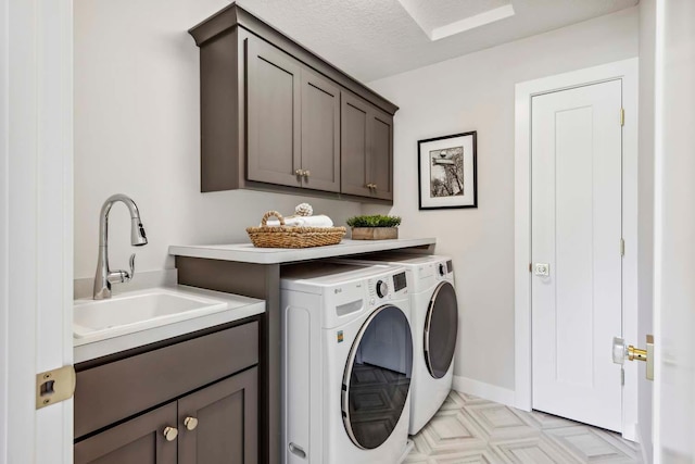 laundry room featuring sink, a textured ceiling, washing machine and dryer, and cabinets