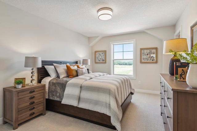 bedroom with a textured ceiling and light colored carpet