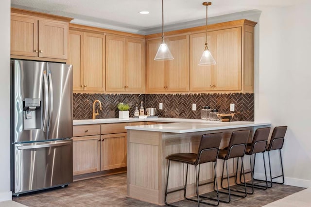 kitchen with light brown cabinets, stainless steel refrigerator with ice dispenser, and hanging light fixtures