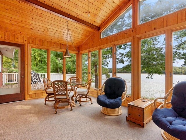 sunroom / solarium with a water view, plenty of natural light, and vaulted ceiling with beams