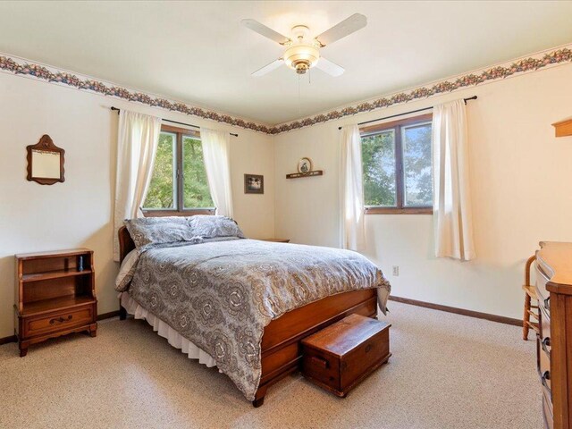 bedroom with light carpet, multiple windows, and ceiling fan