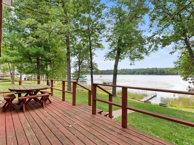 wooden terrace featuring a water view and a lawn