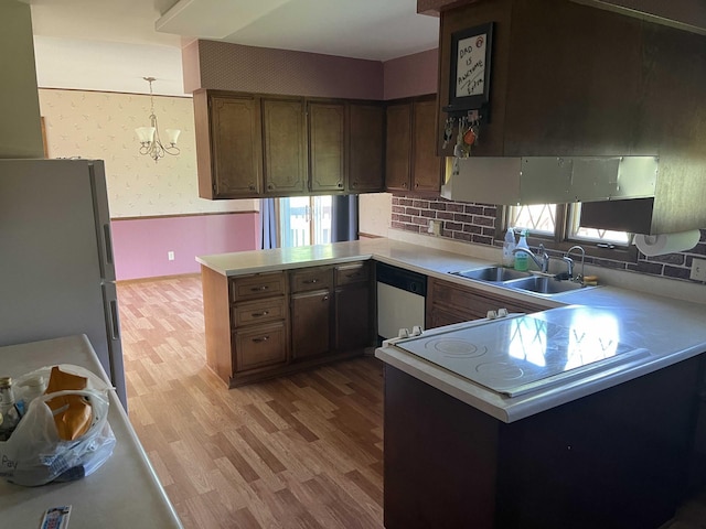 kitchen with kitchen peninsula, sink, white refrigerator, and an inviting chandelier