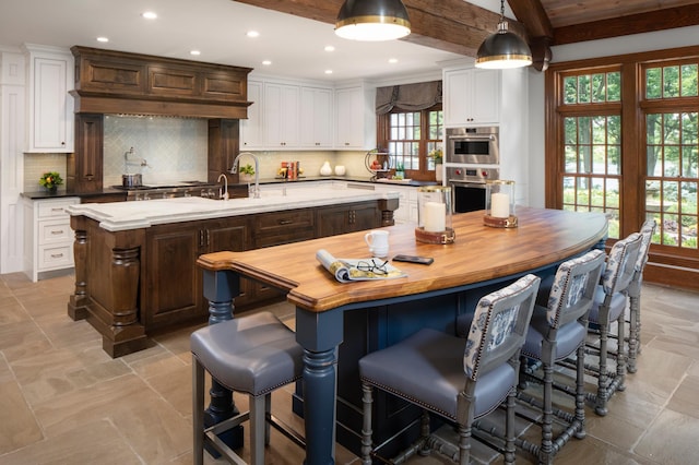 kitchen with tasteful backsplash, dark brown cabinets, pendant lighting, and a center island with sink