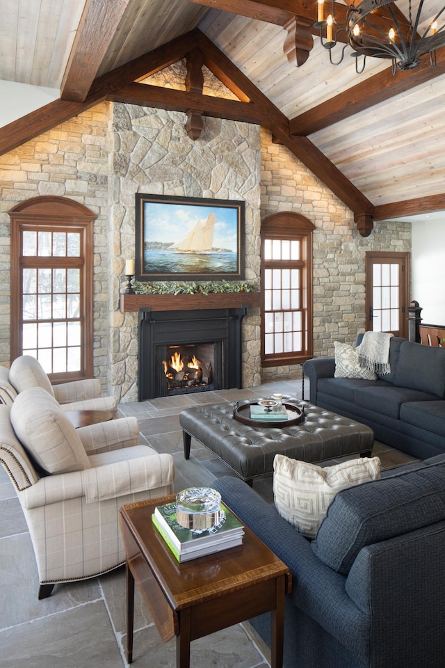 living room featuring lofted ceiling with beams, an inviting chandelier, a stone fireplace, and wooden ceiling