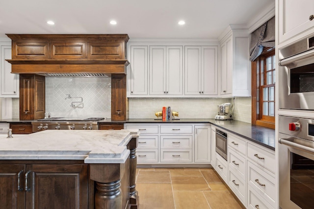 kitchen featuring tasteful backsplash, dark stone countertops, stainless steel appliances, and white cabinetry