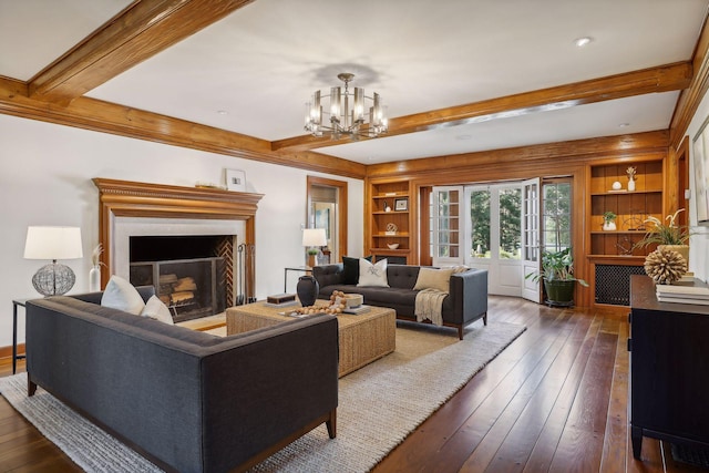 living room with built in shelves, dark hardwood / wood-style flooring, and a chandelier