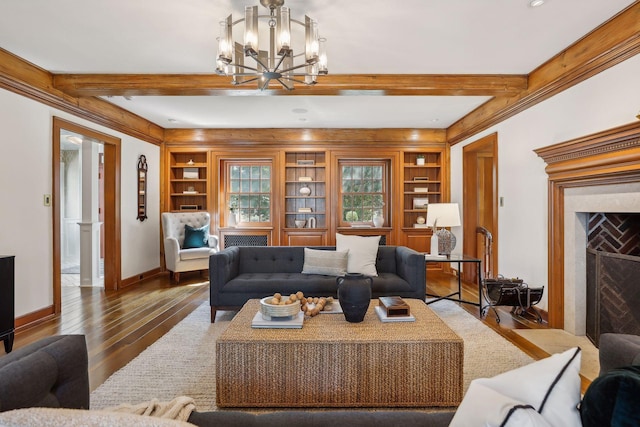 living room featuring built in shelves, a notable chandelier, hardwood / wood-style floors, and a fireplace