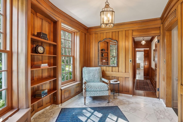 sitting room with built in features, wood walls, and a notable chandelier