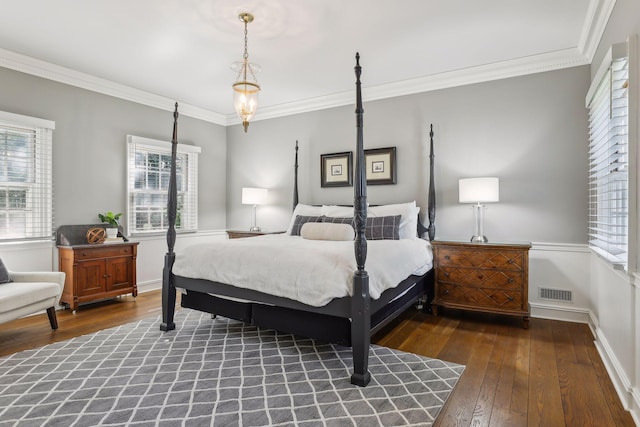 bedroom with multiple windows, dark hardwood / wood-style floors, and ornamental molding