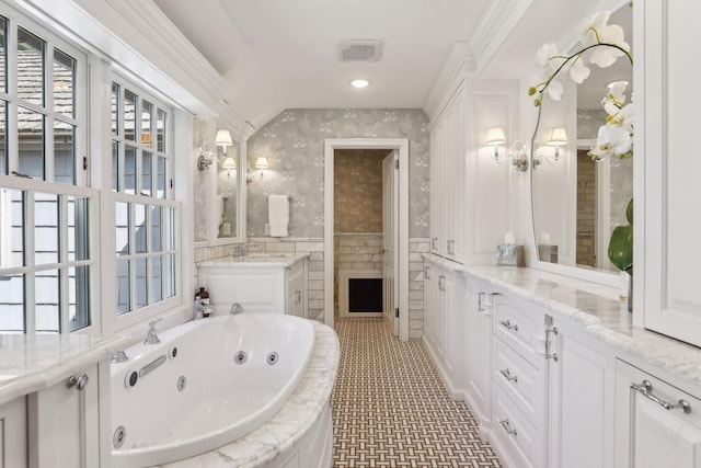 bathroom with ornamental molding, a tub to relax in, and vanity