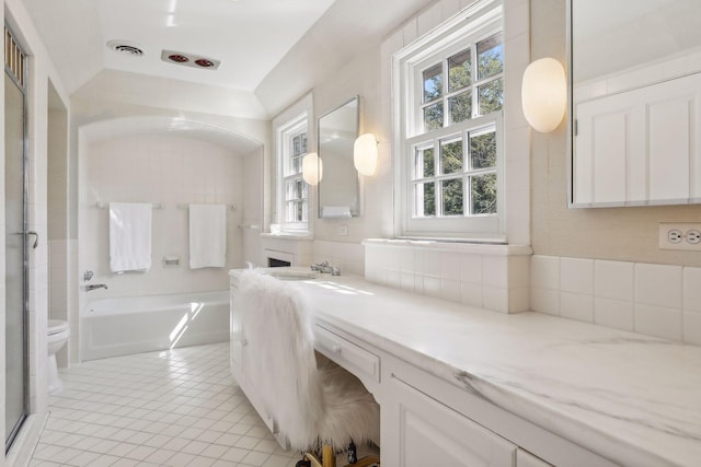 bathroom featuring a tub, toilet, vanity, and tile patterned flooring