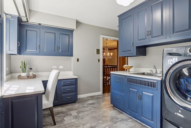 laundry room featuring an inviting chandelier, hardwood / wood-style floors, cabinets, washer / clothes dryer, and sink