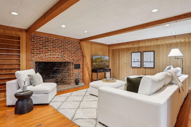 living room with wood-type flooring, a fireplace, beamed ceiling, and wooden walls