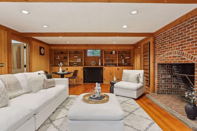 living room with a fireplace, beam ceiling, wooden walls, hardwood / wood-style flooring, and built in shelves