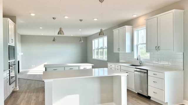 kitchen featuring white cabinets, pendant lighting, a center island, and a healthy amount of sunlight