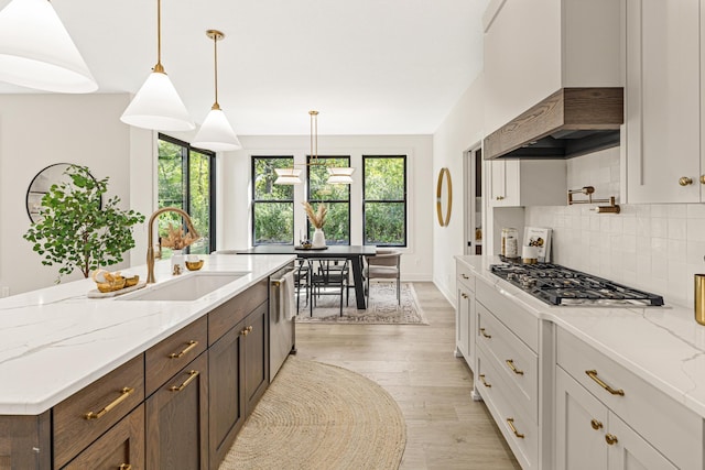 kitchen featuring decorative light fixtures, stainless steel appliances, sink, light wood-type flooring, and white cabinets