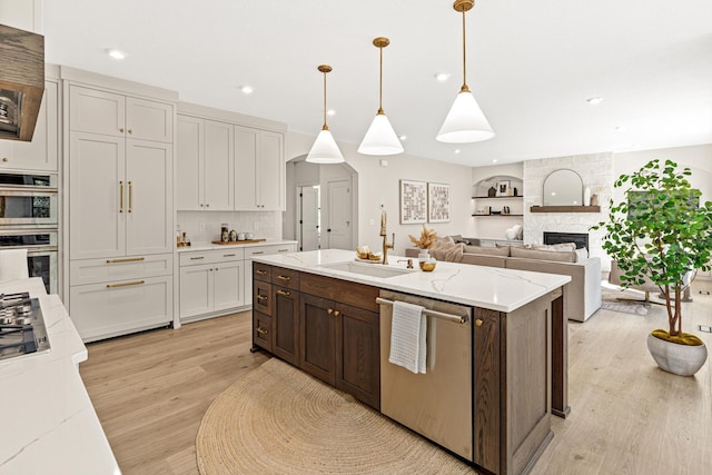 kitchen featuring a center island, light hardwood / wood-style flooring, appliances with stainless steel finishes, sink, and a stone fireplace