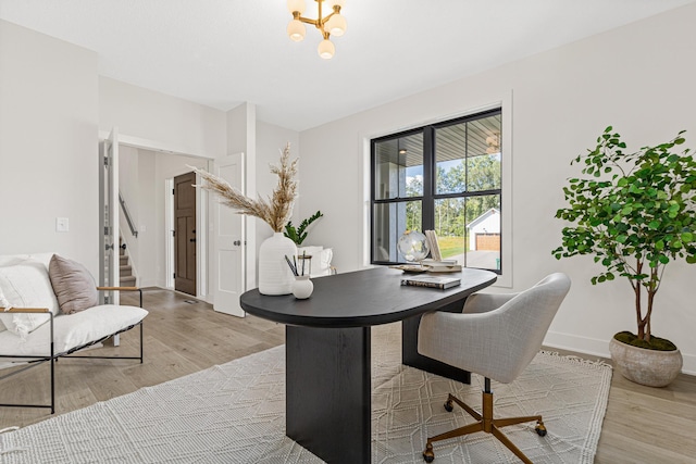 home office featuring an inviting chandelier and light hardwood / wood-style floors