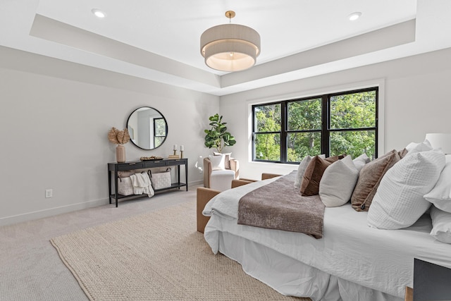 bedroom with a raised ceiling and light carpet