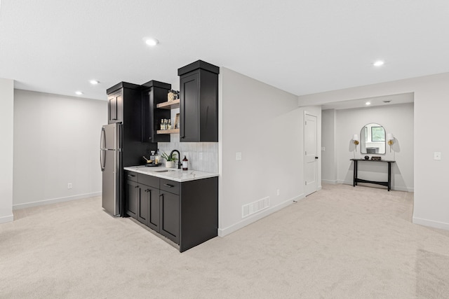 kitchen with stainless steel fridge, light colored carpet, decorative backsplash, and sink