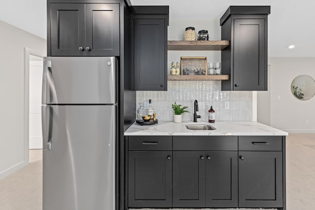 kitchen featuring light colored carpet, sink, stainless steel refrigerator, and light stone countertops