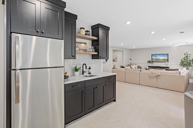 kitchen featuring light stone countertops, stainless steel fridge, light carpet, tasteful backsplash, and sink