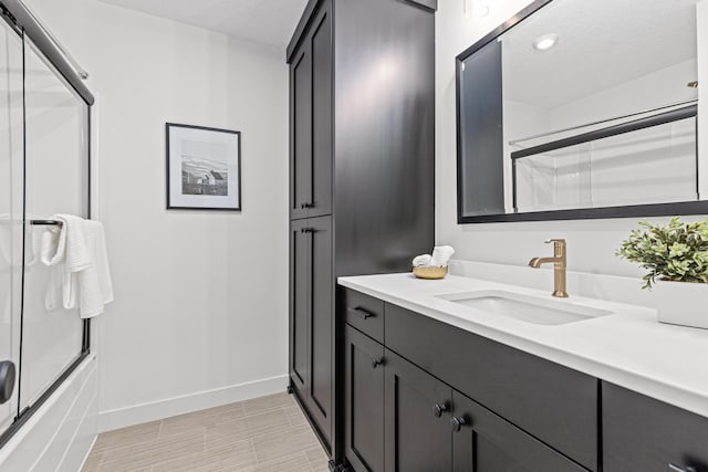 bathroom featuring shower / bath combination with glass door, vanity, and a textured ceiling