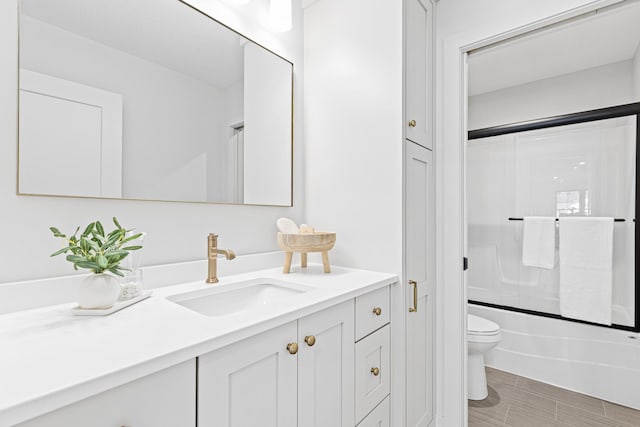 full bathroom featuring vanity, toilet, and bath / shower combo with glass door