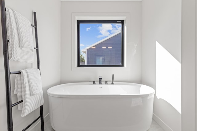 bathroom featuring tile patterned flooring, a healthy amount of sunlight, and a bathtub