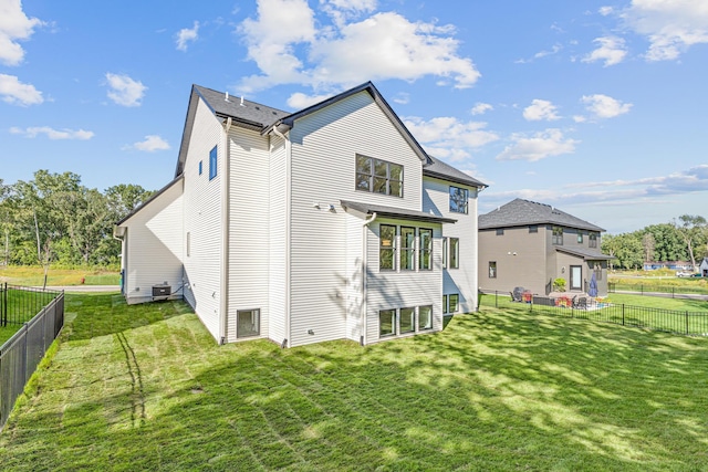 rear view of property with central AC unit and a yard