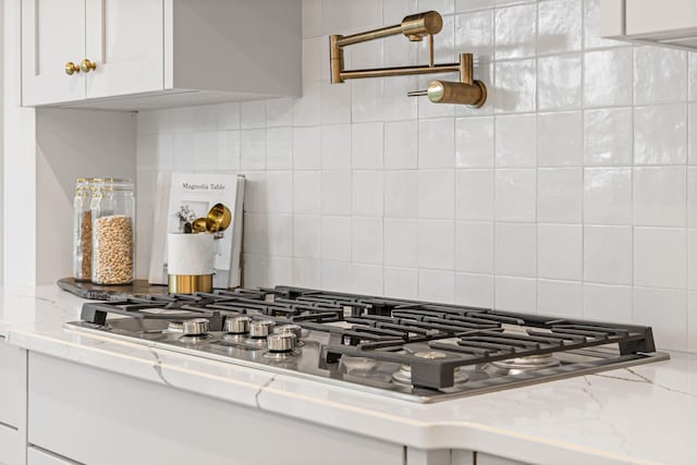 details featuring white cabinetry, light stone counters, and backsplash