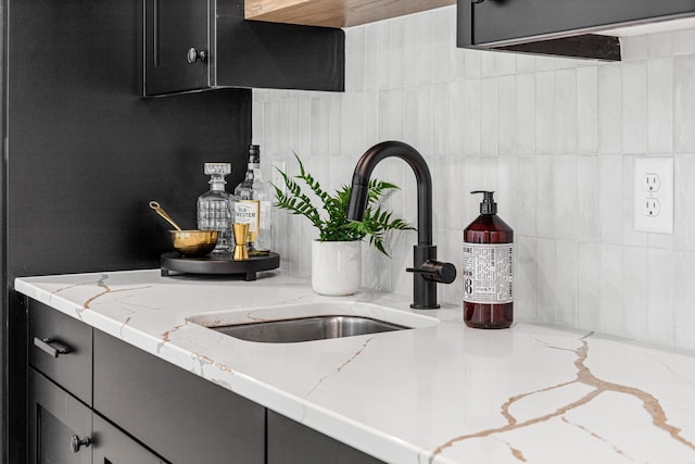 details featuring sink, light stone countertops, and decorative backsplash