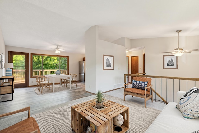 living room featuring light wood-type flooring, vaulted ceiling, and ceiling fan