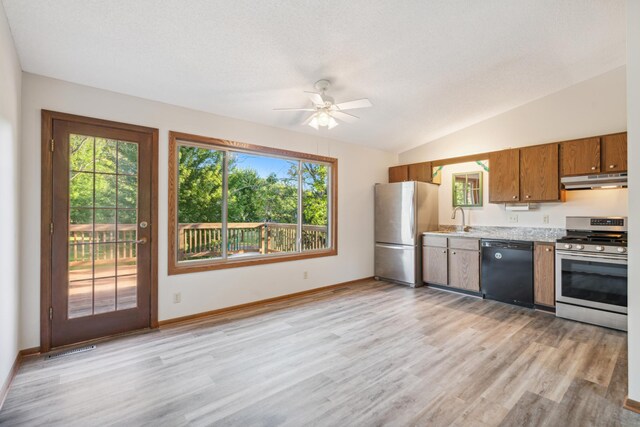 kitchen featuring ceiling fan, vaulted ceiling, stainless steel appliances, and light hardwood / wood-style flooring