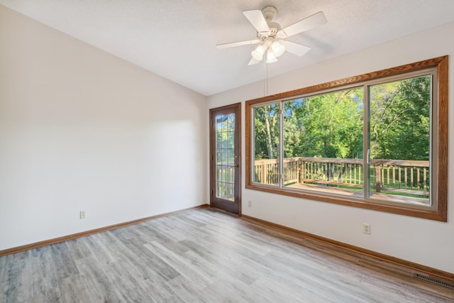 spare room with a textured ceiling, light hardwood / wood-style floors, ceiling fan, and a healthy amount of sunlight