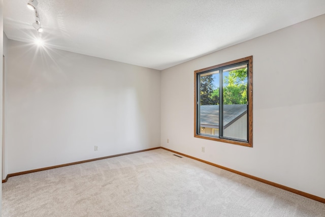 carpeted empty room featuring a textured ceiling