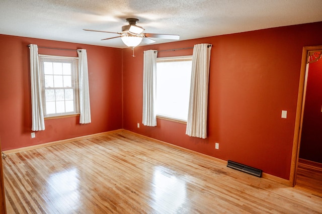 spare room with a textured ceiling, ceiling fan, and light hardwood / wood-style flooring