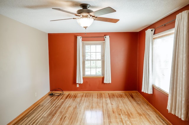 empty room with light hardwood / wood-style flooring, a textured ceiling, ceiling fan, and plenty of natural light