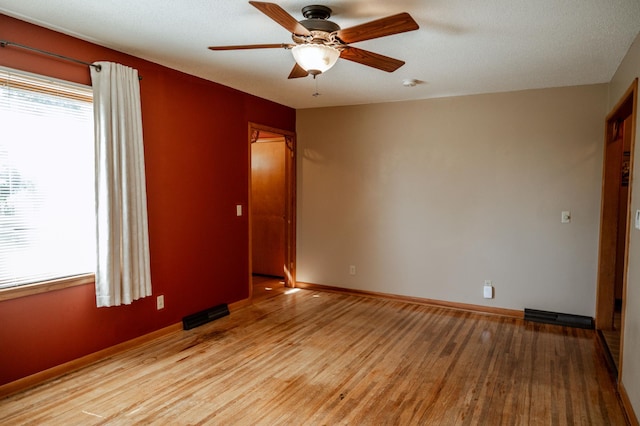 empty room featuring a textured ceiling, light wood-type flooring, and ceiling fan