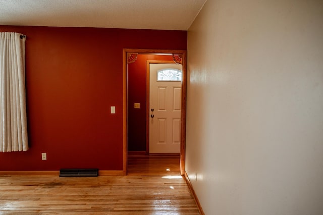 hall featuring a textured ceiling and light hardwood / wood-style flooring