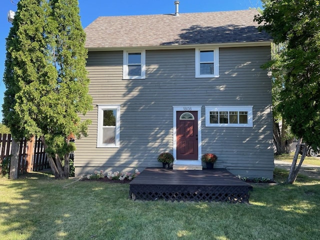 back of property with a lawn and fence