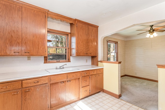 kitchen featuring ceiling fan, sink, and light colored carpet