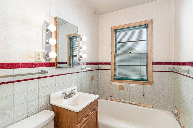 bathroom featuring vanity, toilet, a tub to relax in, and tile walls