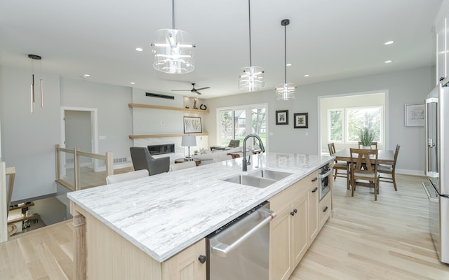 kitchen with appliances with stainless steel finishes, plenty of natural light, a kitchen island with sink, and light hardwood / wood-style flooring