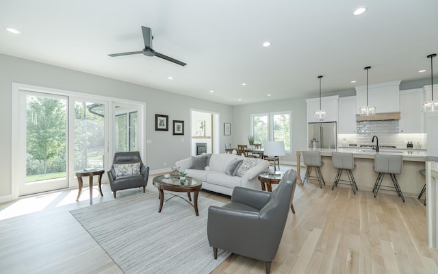 living room with light hardwood / wood-style flooring, ceiling fan, and sink