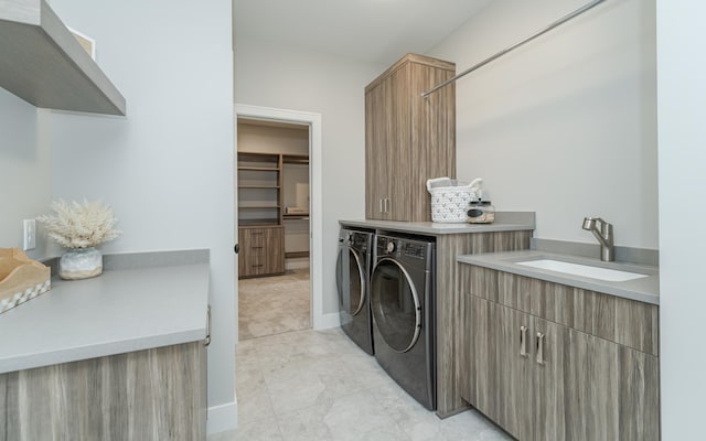 washroom with washing machine and clothes dryer, cabinets, and sink