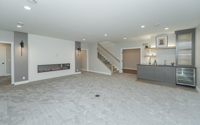 unfurnished living room featuring light colored carpet, beverage cooler, and indoor wet bar